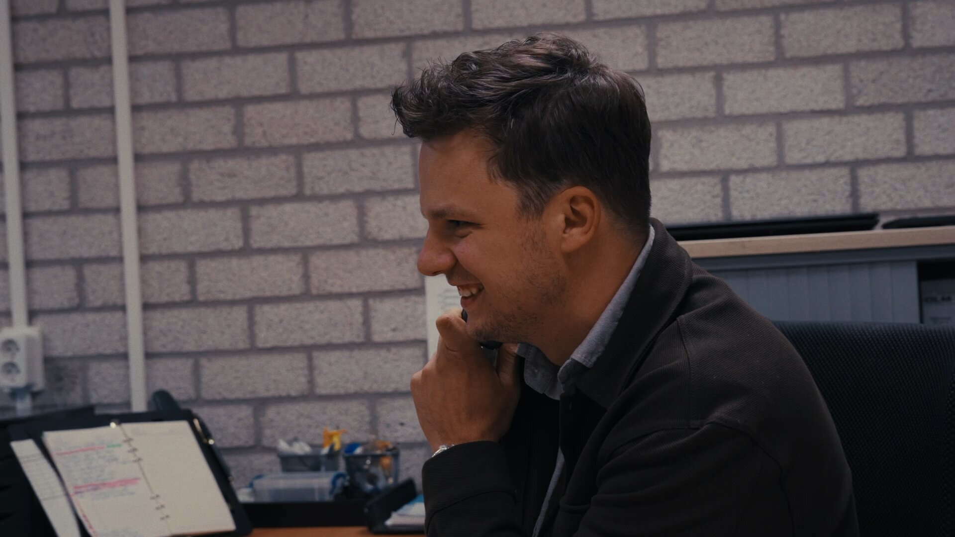 Collega op kantoor lacht tijdens een telefoongesprek aan het bureau.