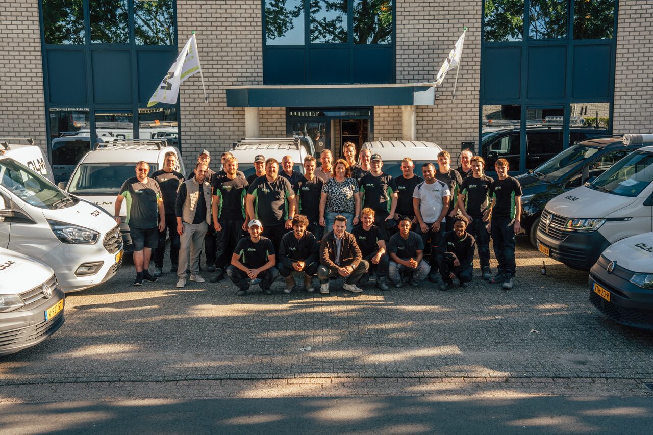 Het team van Van Olm Elektrotechniek poseert met de bussen voor het bedrijfspand.