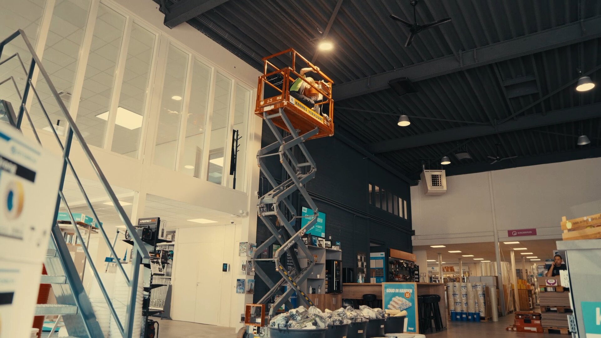 Monteur op een schaarhoogwerker werkt aan het plafond van de winkel van Stukbouw.